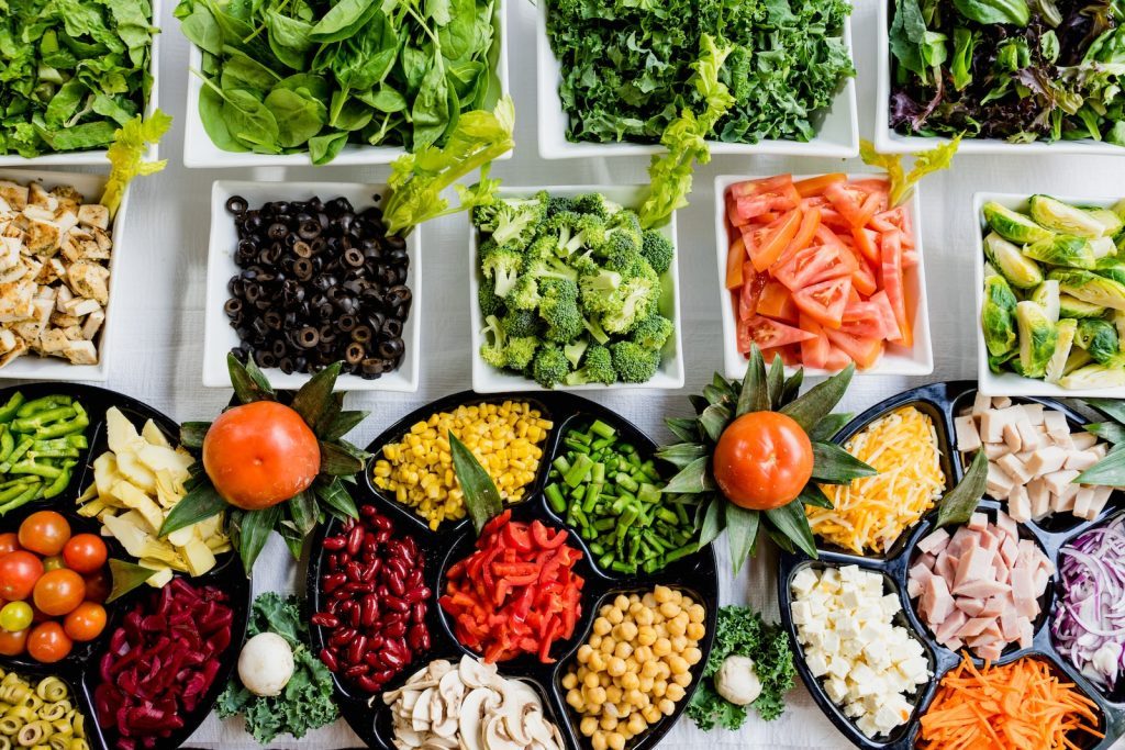 Une variété de salades et de légumes sur une table.