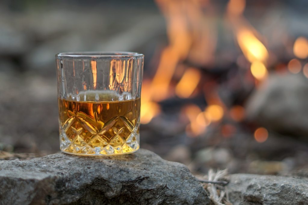 Un verre de whisky sur un rocher devant un feu.