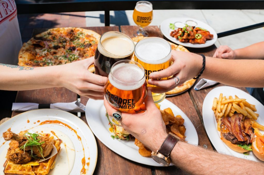 Un groupe de personnes trinquant à une table avec de la nourriture et de la bière.