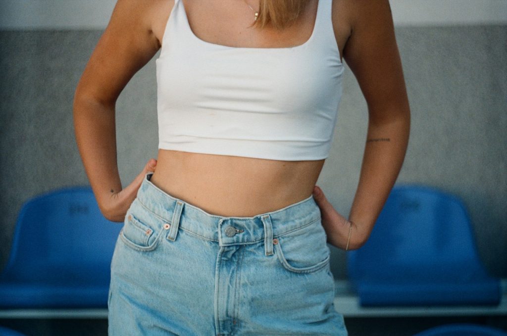 Une femme portant un crop top blanc et un jean bleu.